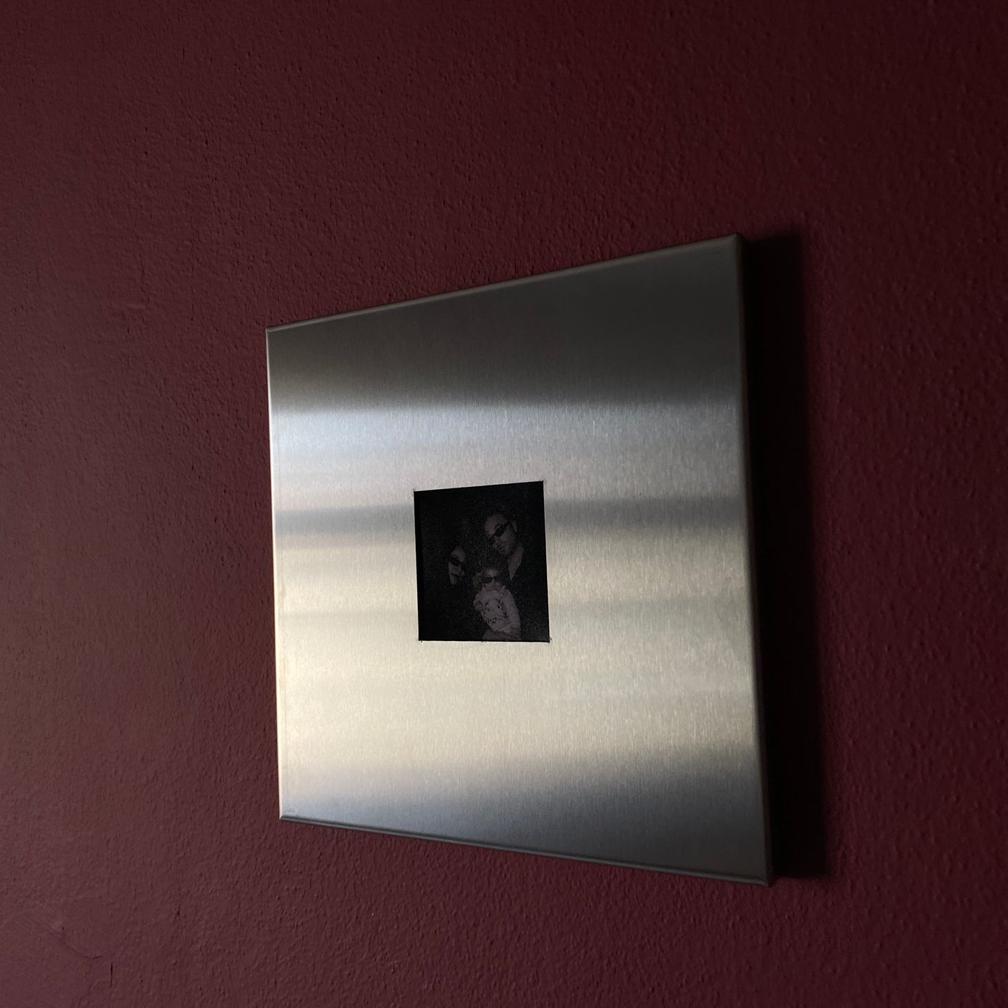 Minimal stainless steel magnetic photo frame hung on a dusty pink wall