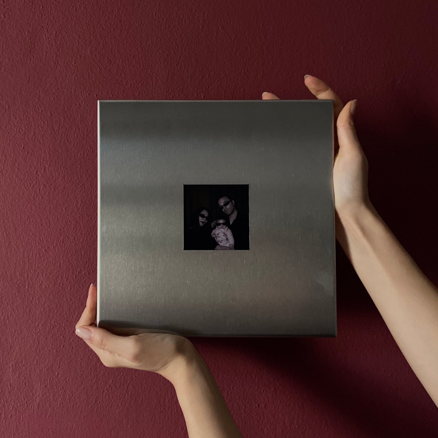 Hand placing stainless steel magnetic photo frame on wall side view