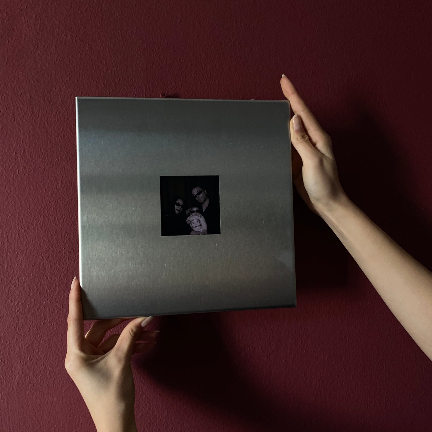 Stainless steel magnetic photo frame being mounted on wall close up